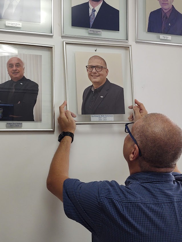 Rui Schürmann toma posse para seu segundo mandato à frente da ABIH-SC a foto ele está pendurando seu quadro na galeria de presidentes